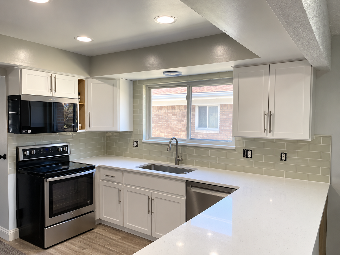 White kitchen cabinets with white countertops, tile backsplash and stainless steel appliances
